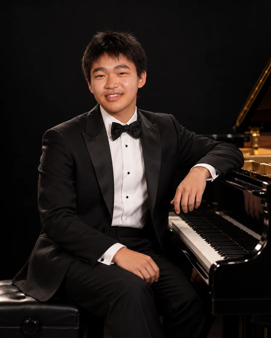 Cameron Lu seated beside a grand piano